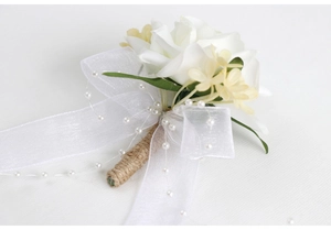 Détail de la boutonnière de mariage avec rose blanche, ruban organza et perles