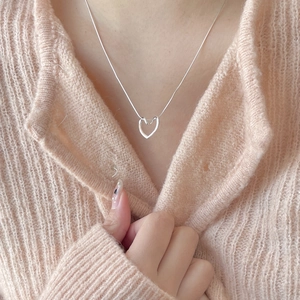Close-up of a minimalist 925 sterling silver heart pendant on a sleek snake chain