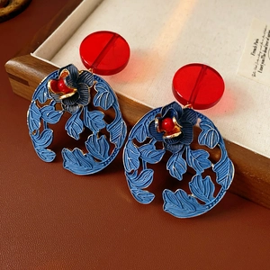 Detail of vintage round floral earrings featuring red and blue enamel with gold accents