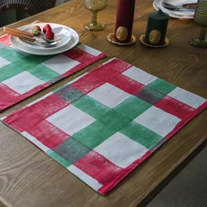 Classic red and green Christmas plaid placemats set on a dark wood dining table