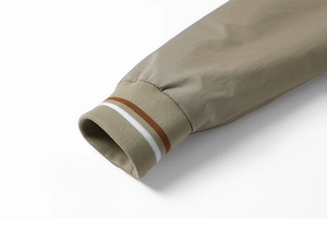 Detail of khaki jacket ribbed cuffs with brown and white sport stripes on polyester fabric