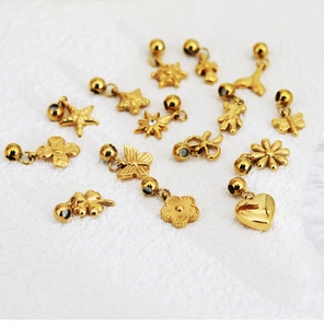 Golden stainless steel charms in flower and butterfly shapes on white fabric