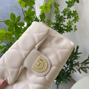Detailed close-up of quilted cream handbag featuring a golden metallic CD buckle design