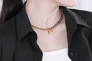 Detail of two-tone gold and silver chain necklace with heart pendant on model