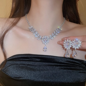 Detail of silver zirconia leaf necklace and drop earrings set worn by a model