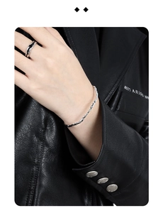 Detailed view of s925 silver wavy texture bracelet and minimalist ring on black leather