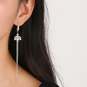Close-up of silver tassel earrings with tree of life design worn by a model