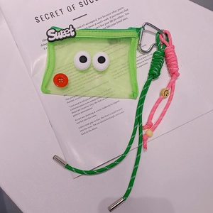 Détail du mini sac en maille verte avec yeux de dessin animé et porte-clés tressé