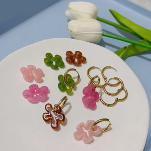Boucles d'oreilles fleurs en résine colorée avec anneaux en or 18 carats sur plat blanc