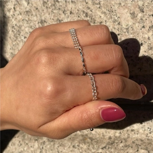 Detail showing a stack of silver beaded and anchor link rings on textured stone