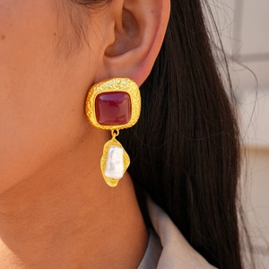 Close-up of vintage geometric red resin earrings with baroque pearls worn by a model