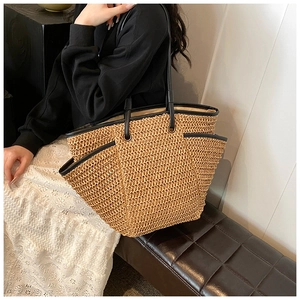 Detail of woven straw tote bag with black faux leather trim and spacious side pocket