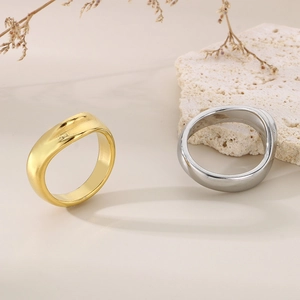 Dettaglio artistico di anelli minimalisti a onde in finitura oro e argento