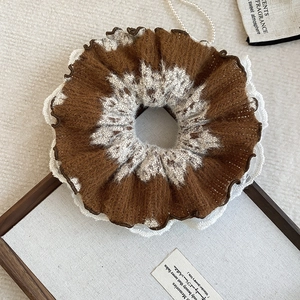 Close-up of plush brown and white hair scrunchie with delicate white lace edging detail