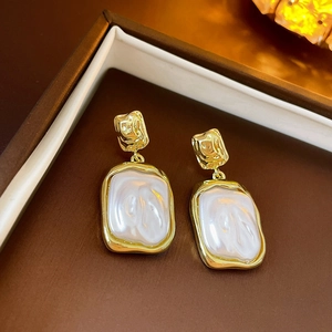 Detailed close-up of golden vintage heart earrings with textured metal and pearl inlays
