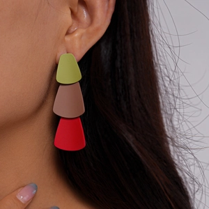 Detail view of three-tier geometric earrings in matte green, tan, and red colors