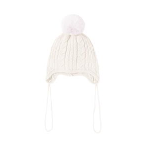 Detail view of cream white knit baby hat featuring chunky cable pattern and a large faux fur pompom