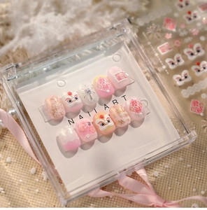 Detail of pink Lion Dance press-on nails with 3D embossed lion head and gold festive patterns