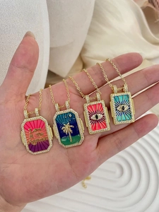 Detail of bohemian gold-plated tarot necklaces featuring colorful enamel and evil eye charms