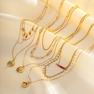 Layered gold necklaces with sun coin, turquoise and pearl pendants on silk background