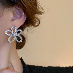 Close-up of elegant silver five-petal flower stud earring with shimmering crystals