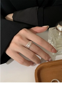 Detail of multi-layered silver geometric ring showing sleek minimalist wrap design