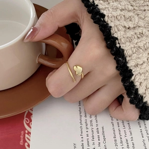 Minimalist 18K gold heart wrap ring with adjustable open design on a stylish hand