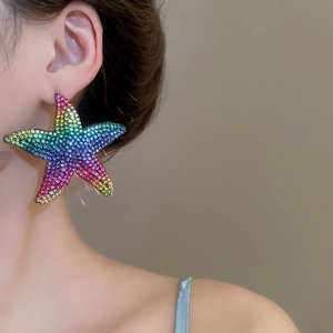 Macro detail of oversized starfish pendant earrings featuring colorful gradient rhinestones