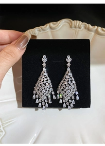Close-up of silver drop tassel earrings with zircon-inlaid hollow rhombus design