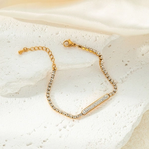 Detailed view of a gold-tone bracelet with white zircons on silk and textured rock