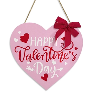 Pink heart-shaped wooden Valentine's Day wall hanging with red bow and festive print