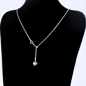 Macro detail of adjustable silver heart pendant with delicate snake bone chain