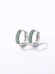 Vue détaillée de boucles d'oreilles créoles argentées serties de trois rangs de zircons verts