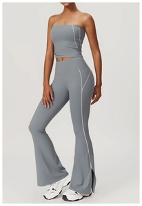 Detail view of high-waist flared yoga pants with white contrast stitching and split hem