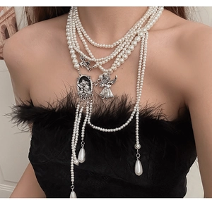 Detail of layered pearl necklace with angel pendant and tassel on black feather top