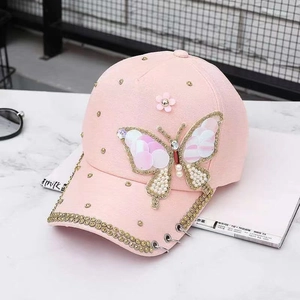 Vue détaillée d'une casquette rose avec sequins papillon, perles et anneaux en métal