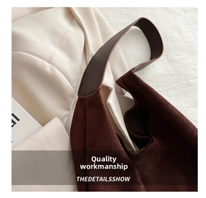 Detail view of dark brown matte suede tote bag on a light blazer with sharp texture focus