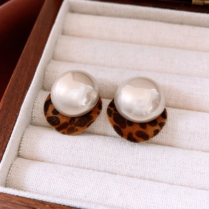 Close-up of leopard print velvet base and round pearl stud earring in wooden box