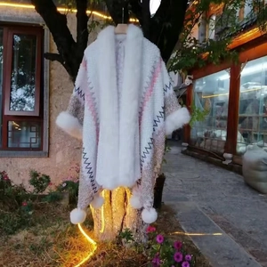 Close-up of knit poncho with faux rabbit fur trim and decorative pom-pom detailing