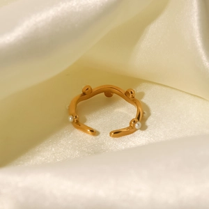 Detailed view of an 18K gold plated irregular wave ring with white pearls on silk fabric