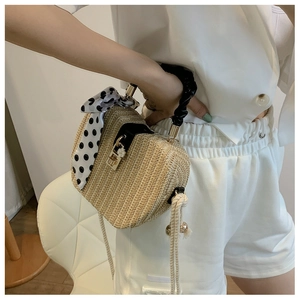 Detail of straw woven bag with black handle, polka dot scarf, and golden metal lock