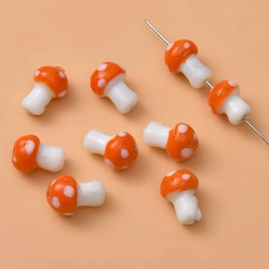 Macro shot of orange glass mushroom beads showing detail of white dots and textures