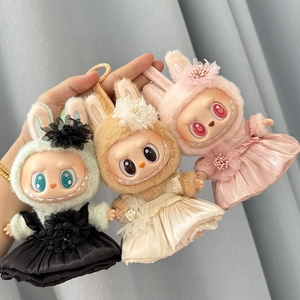 Detailed view of plush doll outfits in green, cream, and pink with floral skirt accents