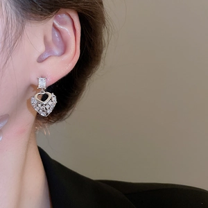 Macro side view of heart-shaped zircon earrings worn by a model in silver finish