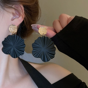 Detailansicht großer mattschwarzer Blumenohrringe mit goldgehämmertem Metallstecker