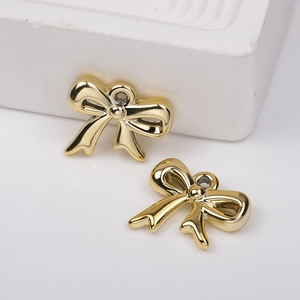 Macro shot of two golden bow-knot metal pendants with glossy finish for DIY jewelry