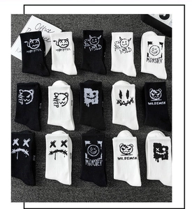 Flat lay of black and white cotton sports socks with various monster graphics