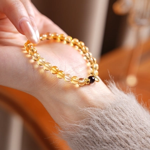 Detailed close-up of amber citrine beaded bracelet with garnet accent on a woman wrist