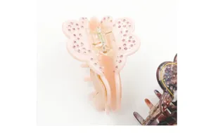 Macro detail of butterfly hair claw clip with pink crystals and metallic spring mechanism