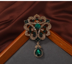 Macro shot of vintage filigree brooch with green gems and brown crystals on bronze metal